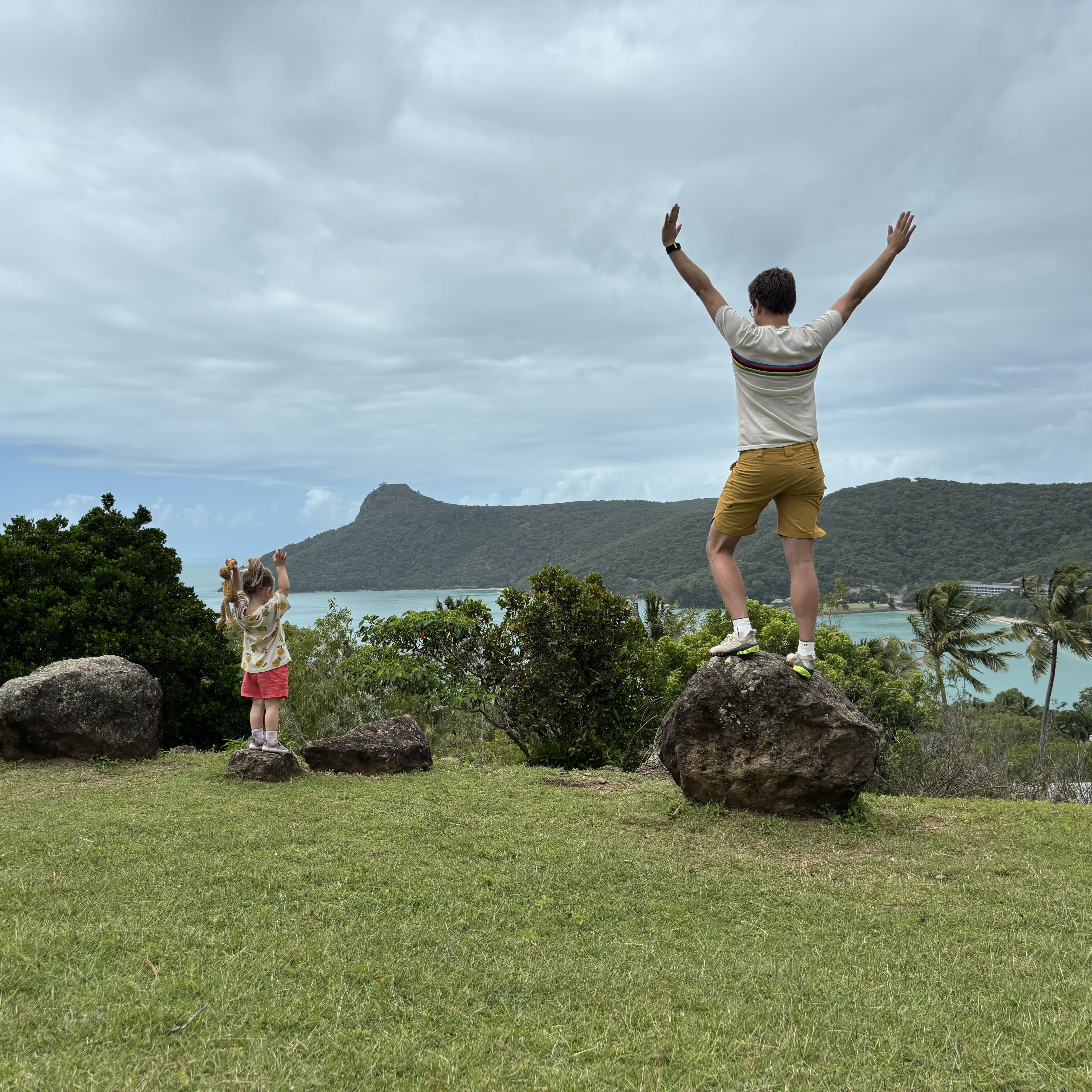 Father and daughter celebrating on rocks above the bay